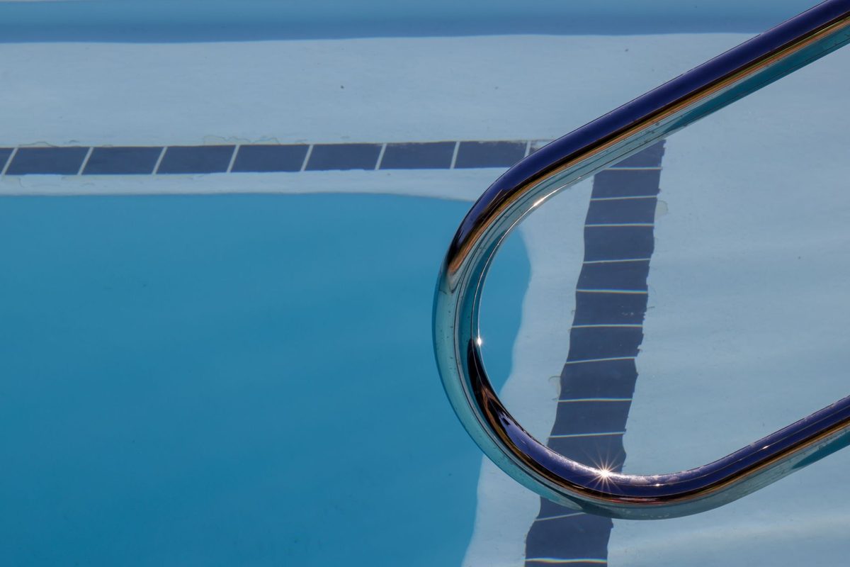 White plaster pool surface with waterline tile and a ladder - how often to resurface a pool in Florida
