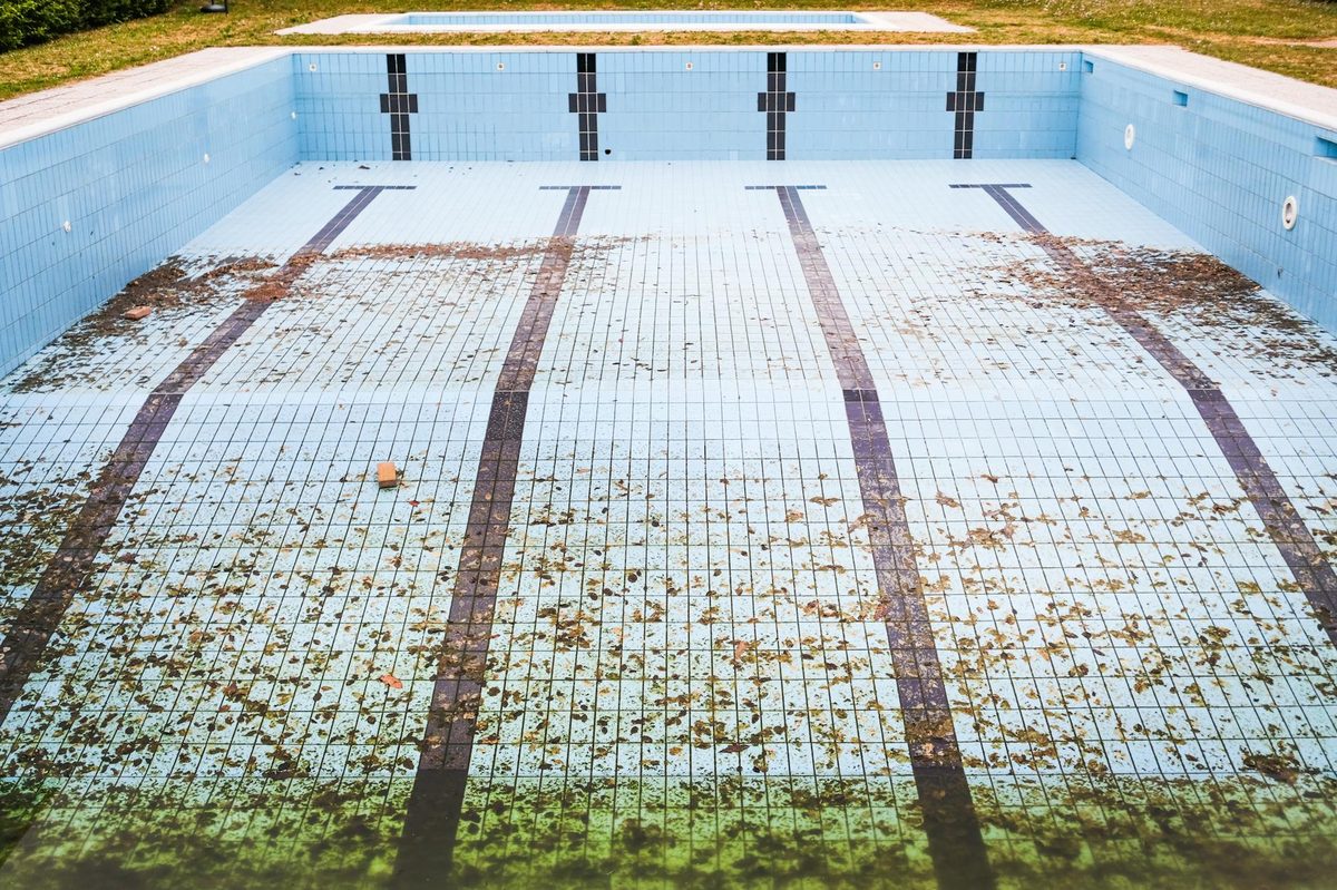 Drained pool with cracked, stained plaster awaiting repair - pool crack and leak repair in Cape Coral, FL