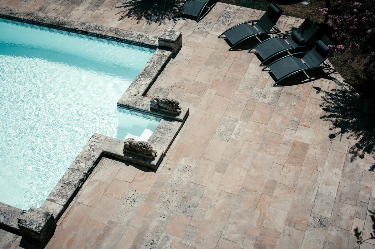 Overhead view of a travertine paver pool deck with loungers - pool deck resurfacing in Cape Coral, FL
